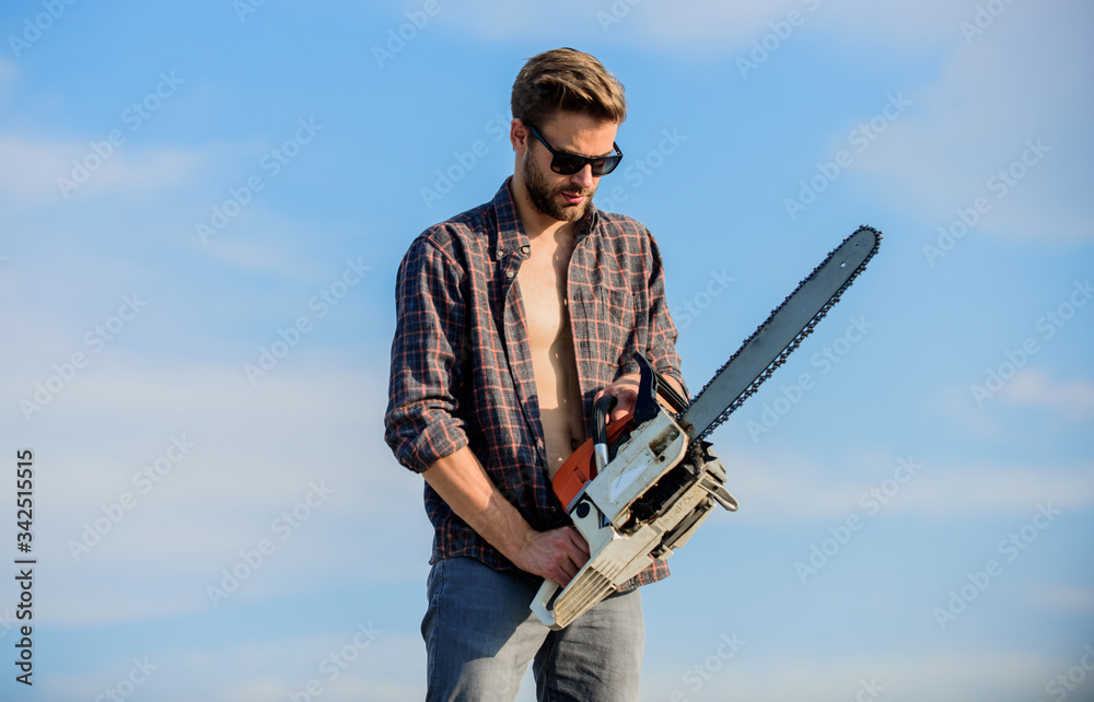 Naklejka premium Dangerous job. men brutality and sexuality. Job for real men. macho man chain saw tool. male work power saw. He fix everything. comfident worker. Mens power. sexy man sky background