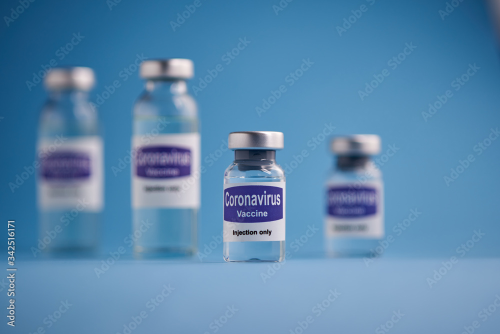 Corona virus vaccine for injection in sealed vials. Vaccine injection in sealed bottles and medical disposable plastic syringe against a blue background.
