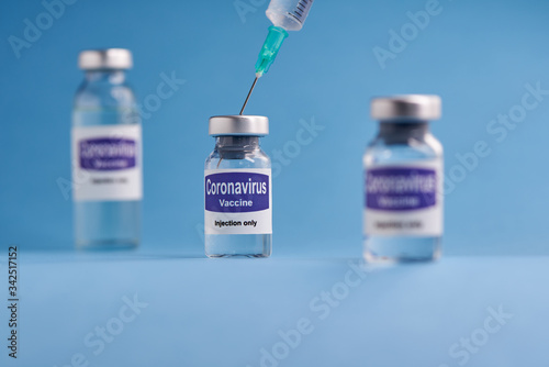Corona virus vaccine for injection in sealed vials. Vaccine injection in sealed bottles and medical disposable plastic syringe against a blue background.
