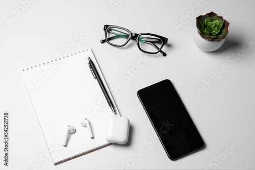 White notebook and black glasses on light background