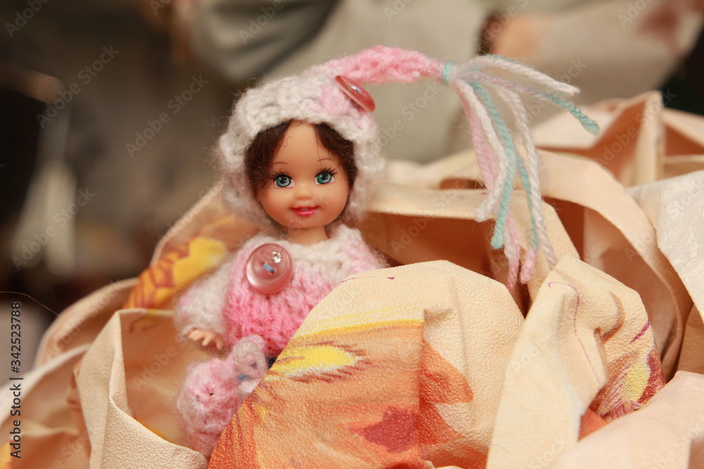 A small beautiful child's doll, posing in beautiful places. 