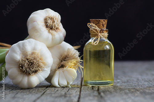 Glass bottle of garlic oil  and Ripe and fresh garlic plant on wooden or rustic table, alternative medicine, organic cleaner. Garlics background ( Allium sativum )