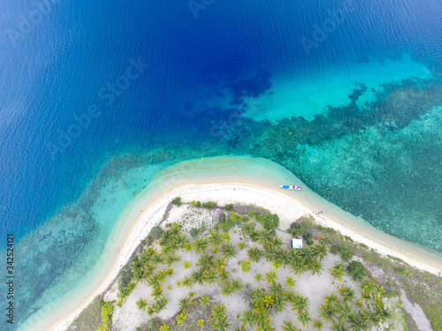 Top view of small isolated tropical island with white sandy beach and blue transparent water and speedboats, longtail boats, coral reefs, Lombok island Indoneseia