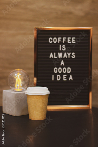 Paper cup cafe take away delivery cement lamp with frame with phrase Coffee is always a good ideia in the wood background  vertical