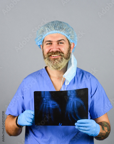 Doctor holds pictures of bones. Fracture and bone damage. Doctor examines radiographic snapshot of wrist. Surgeon estimate damages. Hospital emergency. Doctor compares results. X ray radiation photo