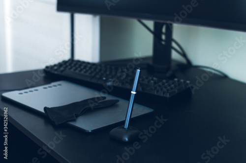 black graphic tablet, monitor and keyboard on a black table and green background, the place of work of a graphic designer at home. Remote work of a modern artist.