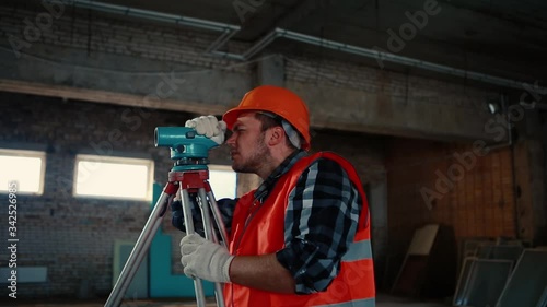 Wallpaper Mural A man in an orange vest and orange helmet looks at the measuring device against the backdrop of a construction site. Torontodigital.ca