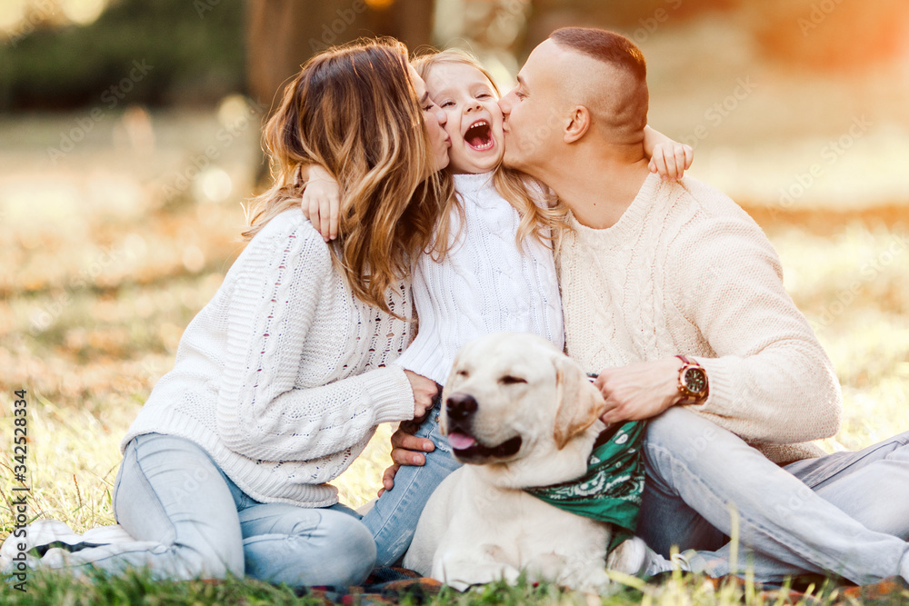 Happy beautiful family with dog labrador is having fun are sitting on green grass in park. Happy beautiful family with dog labrador is having fun are sitting on green grass in park.