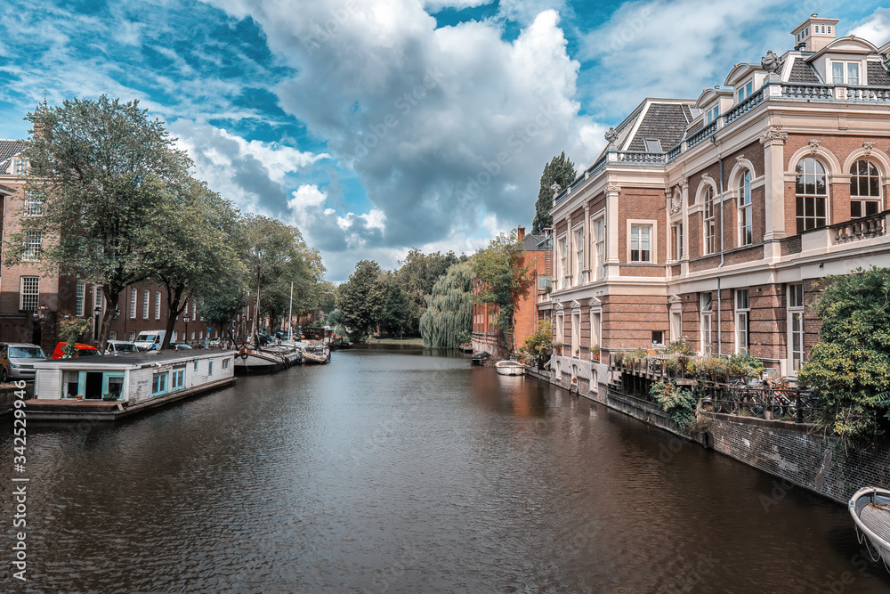 Dutch waterway in Amsterdam with a view of houses and houseboats Dutch waterway in Amsterdam with a view of houses and houseboats