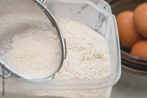 Flour in a plastic bowl close up with some ingredients for baking needs