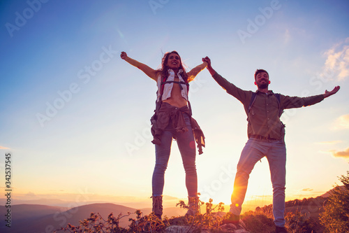 Couple on Top of a Mountain Shaking Raised Hands