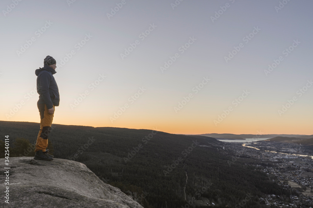 Young man looking at the views form the top of a mountain.