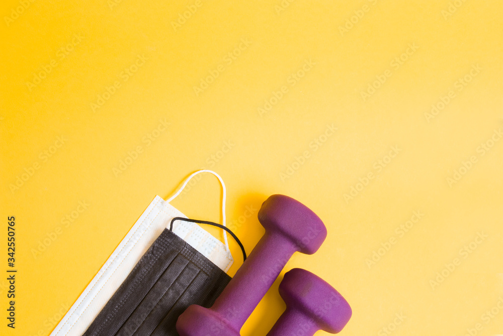 purple dumbbells and medical protective masks of different colors on a yellow background. top view place copy, doing sports at home, healthy lifestyle concept purple dumbbells and medical protective masks of different colors on a yellow background. top view place copy, doing sports at home, healthy lifestyle concept