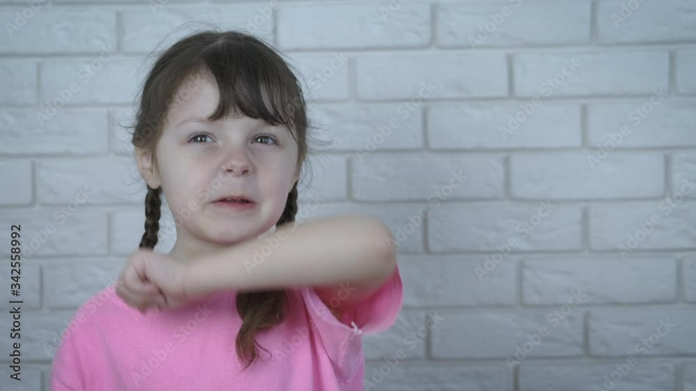 The child is sneezing. A cute little girl sneezes on her elbow. The child is sneezing. A cute little girl sneezes on her elbow.