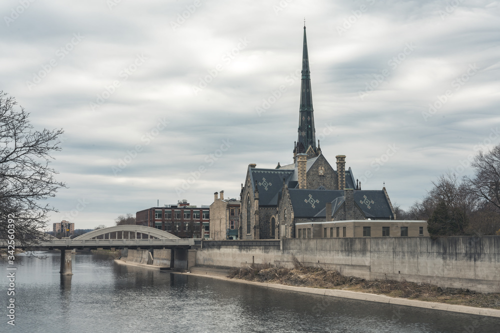 Old Historic Church beside a river with a bridge during cloudy weather 