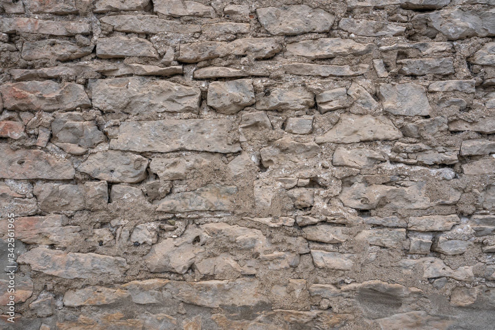 Stone Wall Texture Background with asymmetrical stones stacked together to form a vintage wall