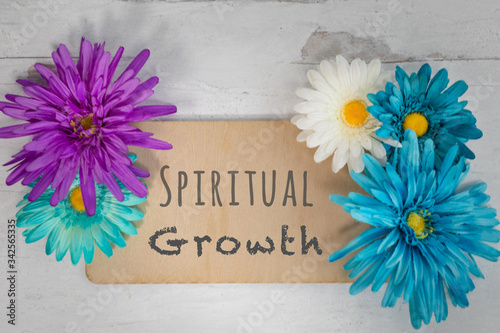 Wooden sign Spiritual growth written on board surrounded by spring bright colorful flowers flat lay design  photo