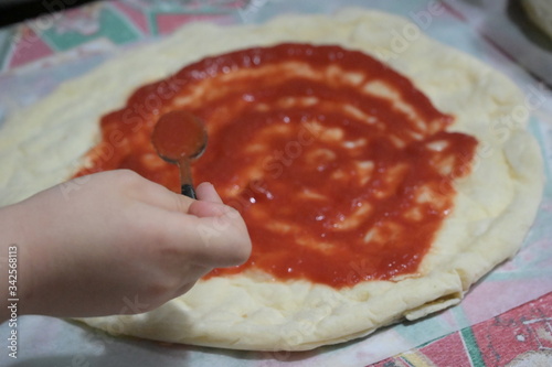 preparazione di una pizza fatta in casa con pomodoro, mozzarella, olive, capperi e olio extra vergine d'oliva