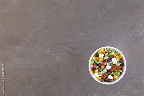 Background of chocolate candy stones lying in a white bowl on a slate board