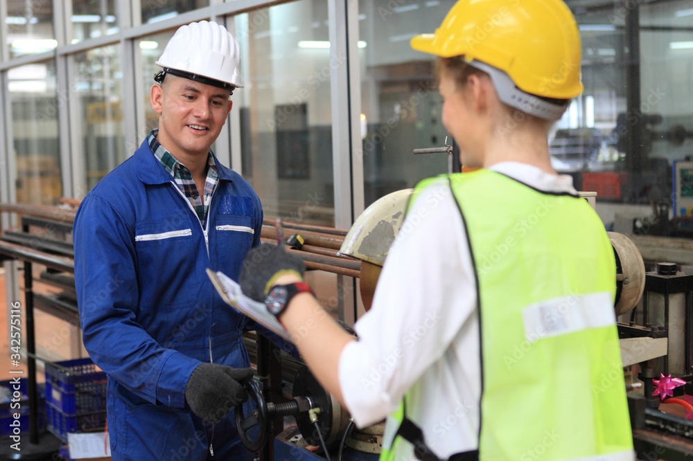 Male and Female Industrial Engineers in Hard Hats Discuss New Project while working on site . They Work in a Heavy Industry Manufacturing Factory. Male and Female Industrial Engineers in Hard Hats Discuss New Project while working on site . They Work in a Heavy Industry Manufacturing Factory.