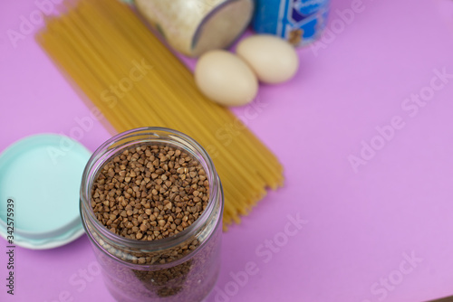 Food stock for quarantine isolation period on purple background. Rice, egg, canned food, buckwheat, spaghetti. Food delivery, Donation. Copyspace
