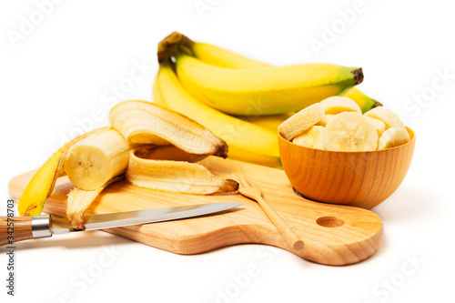 Banana with cut sliced in brown wooden bowl isolated on white background, benefits of banana which contain potassium, high fiber food can help manage blood pressure and reduce strain on cardiovascular