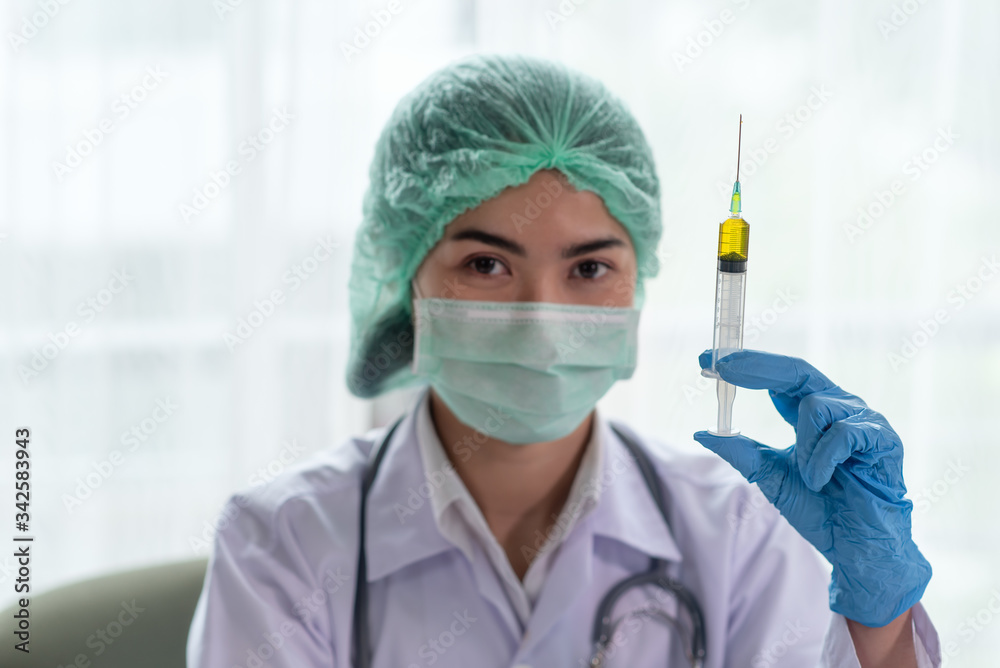 Female doctor with a stethoscope on shoulder holding syringe, Science and chemistry, Healthcare and Medical concept Female doctor with a stethoscope on shoulder holding syringe, Science and chemistry, Healthcare and Medical concept