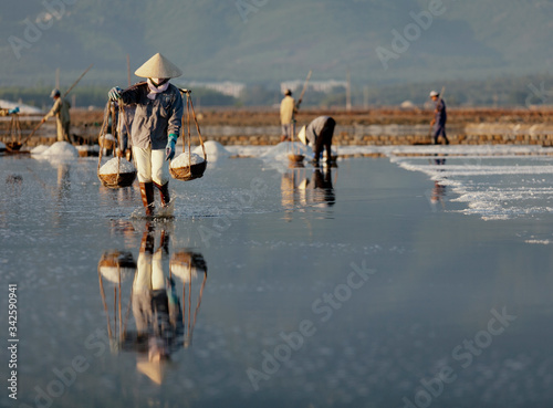 Salt and Silhoutte of salt farmer on salt field Hon Khoi, Nha Trang, Khanh Hoa, Vietnam.