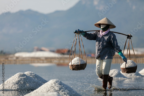 Salt and Silhoutte of salt farmer on salt field Hon Khoi, Nha Trang, Khanh Ho...