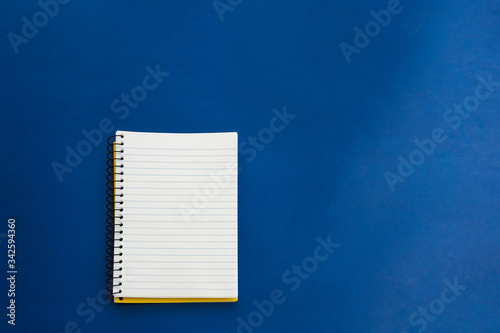 A blank office notebook laying on top of a dark midnight blue background with a soft light hitting from the side