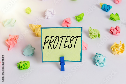 Conceptual hand writing showing Protest. Concept meaning An action expressing disapproval of or objection to something Colored crumpled paper empty reminder white floor clothespin © Artur