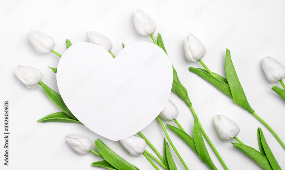 Romantic love layout made with paper card shape of heart and tulips on white pastel background. Template of festive congratulations. Wedding greeting concept.