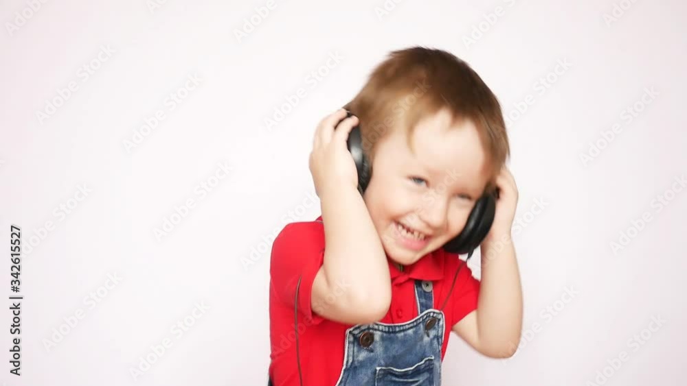 A cute little boy tries to put on headphones and represents like he listen to the music A cute little boy tries to put on headphones and represents like he listen to the music