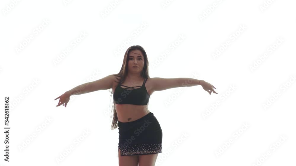 Medium long shot of young beautiful woman with long hair and a beautiful plump figure in a black top and a short black skirt dances belly dance, oriental dance on a white background, isolated Medium long shot of young beautiful woman with long hair and a beautiful plump figure in a black top and a short black skirt dances belly dance, oriental dance on a white background, isolated