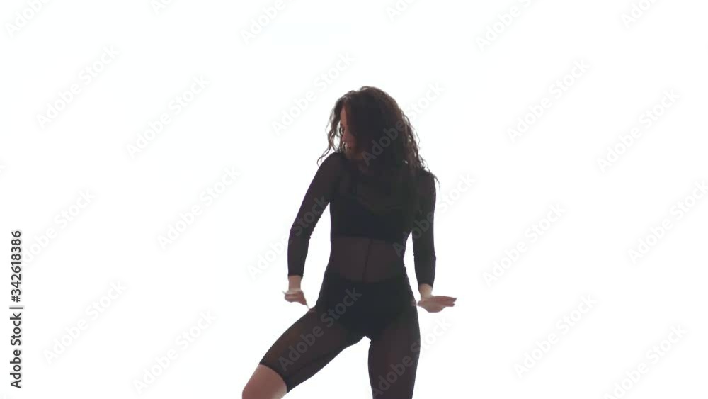 Medium long shot of young beautiful woman in a black transparent tight suit energetically dancing dancehall, street dance, twerk against white background, isolated Medium long shot of young beautiful woman in a black transparent tight suit energetically dancing dancehall, street dance, twerk against white background, isolated
