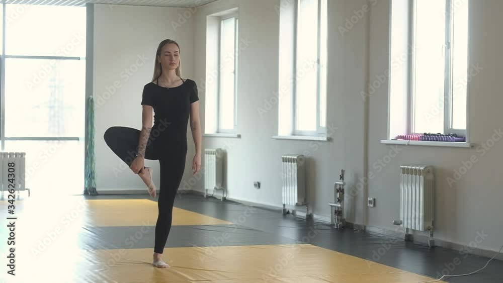 Asana exercise for breathing and concentration and balance. woman meditates in a balance pose in the training room. A slim athletic girl takes a breath.  Relaxation balance and peace of mind.