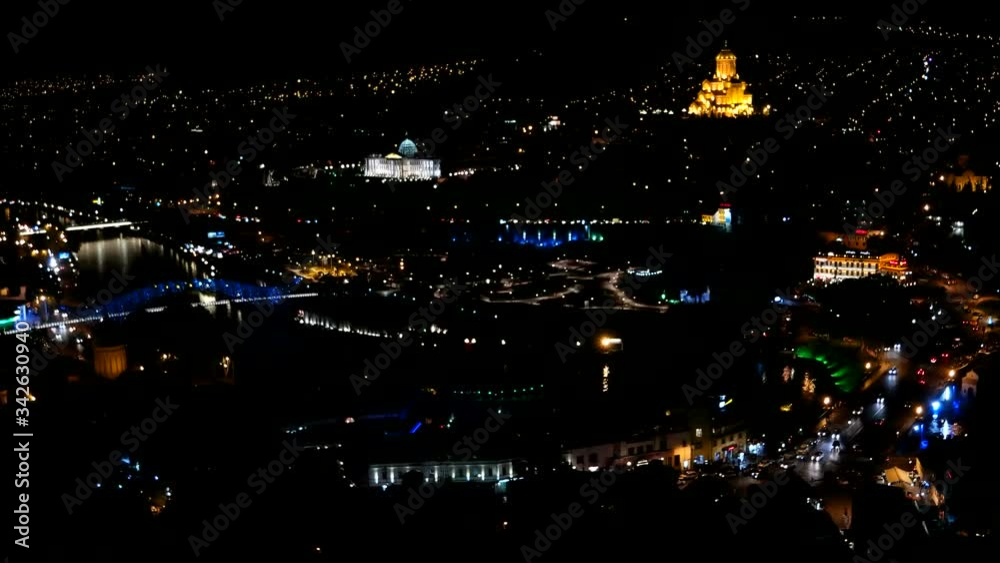Night panorama view of Tbilisi capital of Georgia country. Metekhi church Holy Trinity Cathedral Sameba and Presidential Administration at night with illumination and moving cars Night panorama view of Tbilisi capital of Georgia country. Metekhi church Holy Trinity Cathedral Sameba and Presidential Administration at night with illumination and moving cars