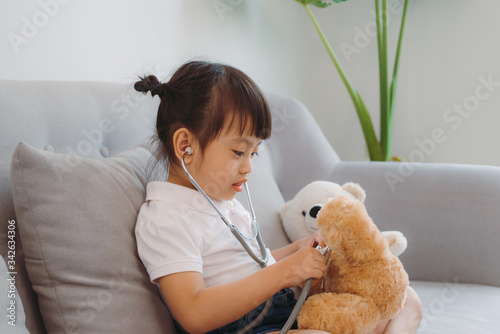 Be attentive. Pleasant pensive busy girl treating plush bear sitting on couch