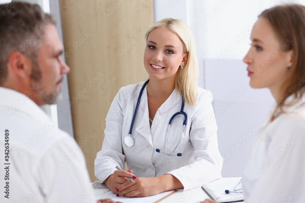 Female family doctor listen carefully young couple in office. Motherhood and child delivery ifv new life abortion therapeutist reception service physical hope emotion hospital expectation