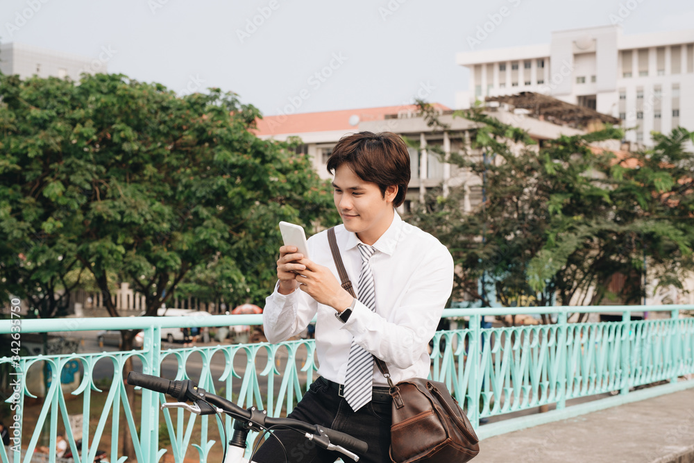 Man standing next to his bike hand holding mobile telephone