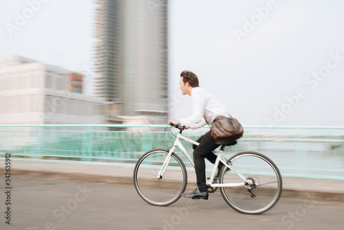 Fototapeta Naklejka Na Ścianę i Meble -  Blurred image of Asian man mad riding bicycle in urban city commuting with speed and hipster trendy transportation