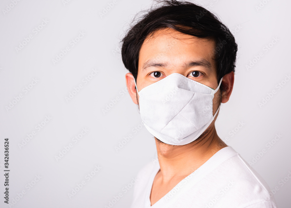 Closeup Asian handsome Man wearing surgical hygienic protective cloth face mask against coronavirus, studio shot isolated white background, COVID-19 medical concept Closeup Asian handsome Man wearing surgical hygienic protective cloth face mask against coronavirus, studio shot isolated white background, COVID-19 medical concept