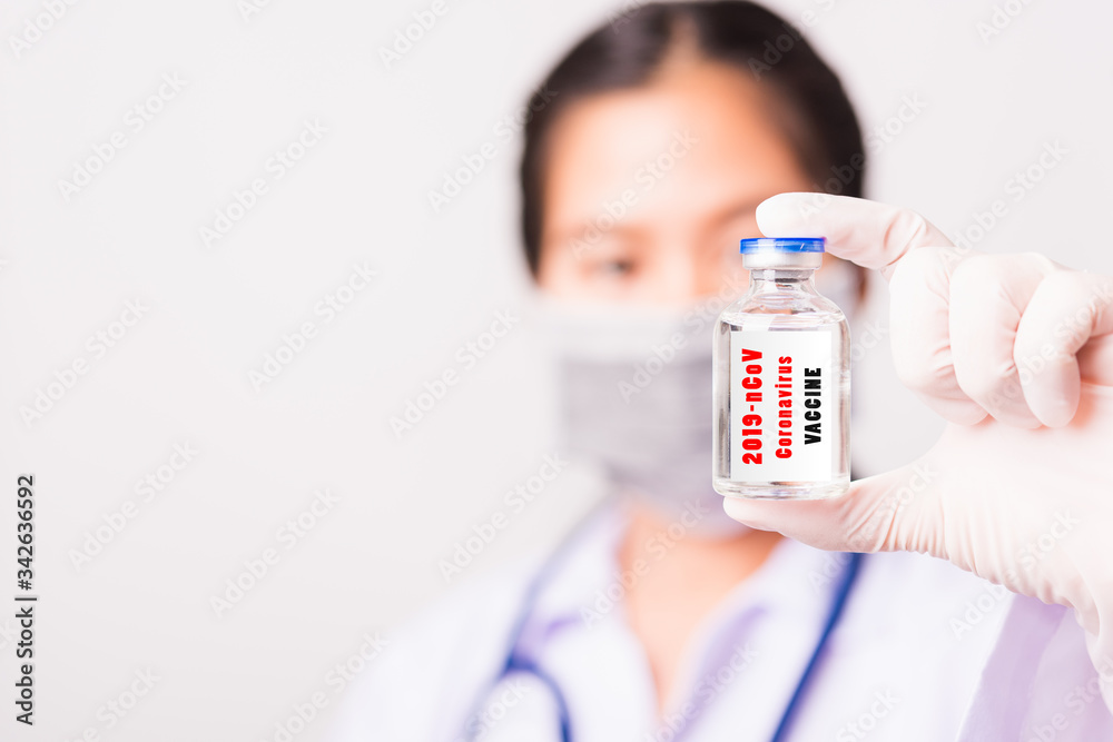 Closeup female woman doctor or scientist in uniform wearing face mask protective in lab use hand finger hold vial vaccine bottle, and on vial vaccine have Closeup female woman doctor or scientist in uniform wearing face mask protective in lab use hand finger hold vial vaccine bottle, and on vial vaccine have
