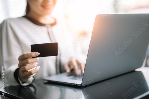 Smiling Asian business women using a laptop computer for online shopping purchase with a credit card