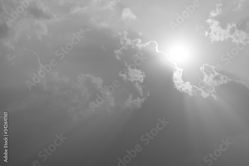 A black and white image of a large cloud covering the sun shining.