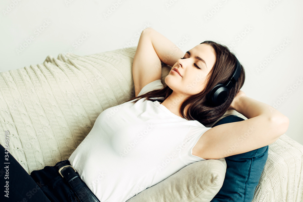 25 year old beautiful girl resting on the couch and listening to the audiobook in the headphones 25 year old beautiful girl resting on the couch and listening to the audiobook in the headphones