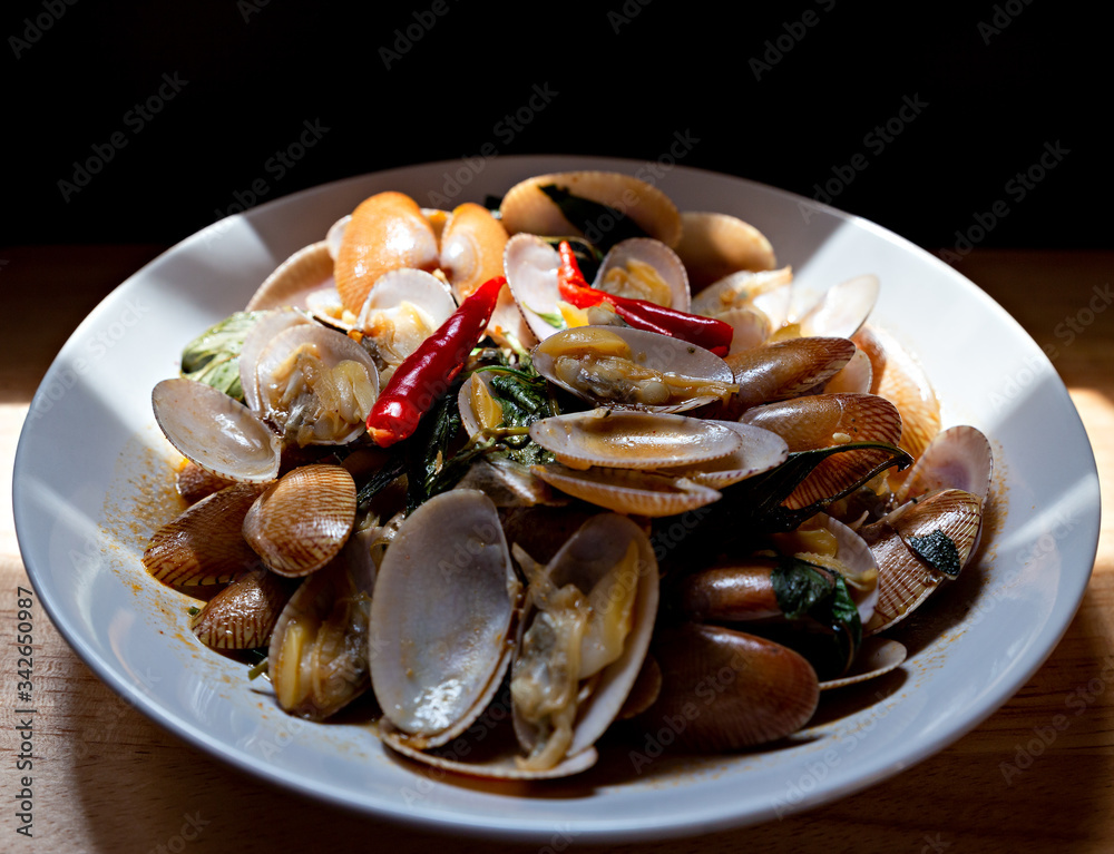 Delicious stir fried clams with chili paste on white plate.Thai food. Delicious stir fried clams with chili paste on white plate.Thai food.