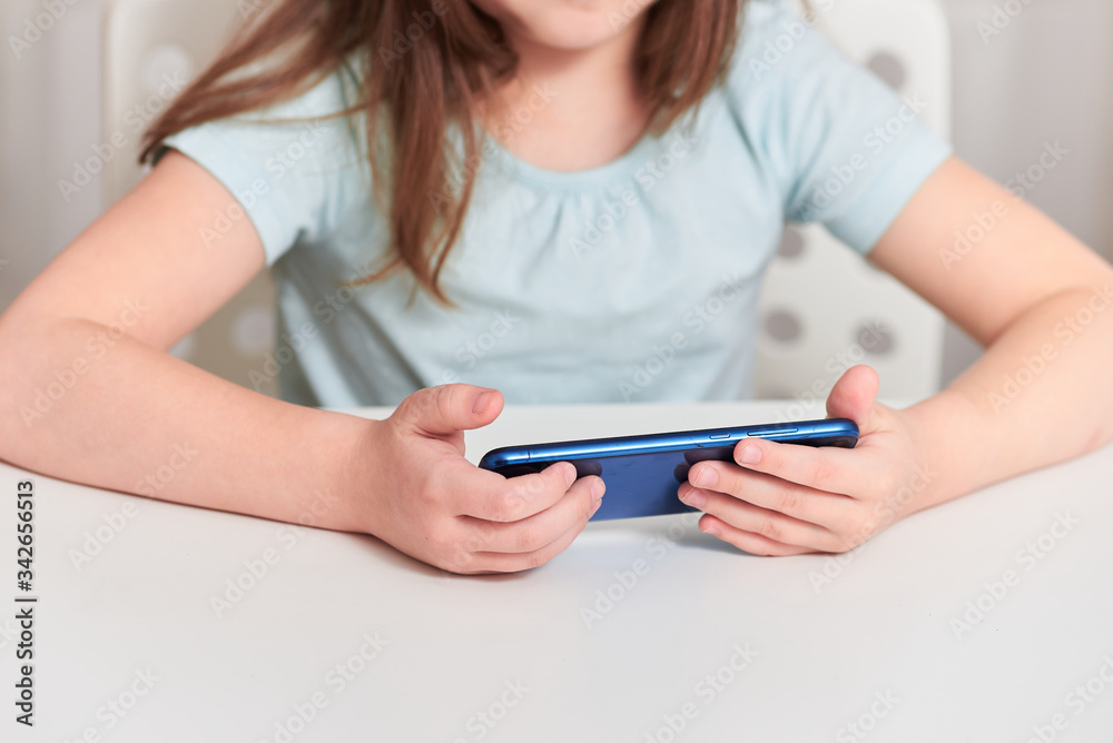 A little girl plays with the phone at home. A little girl plays with the phone at home.