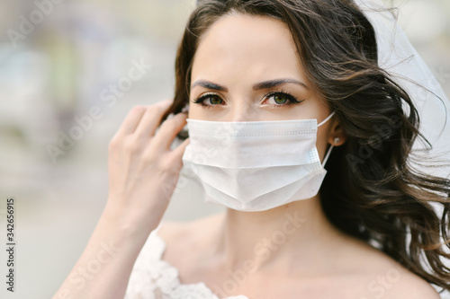 Bride in medical mask on street of city during coronavirus epidemic. Wedding day COVID-19 protection 