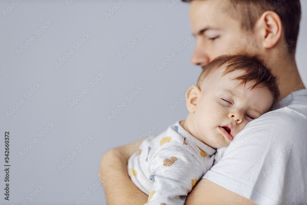 Closeup of adorable little boy sleeping deeply and dreaming while his caring father holding him. Closeup of adorable little boy sleeping deeply and dreaming while his caring father holding him.
